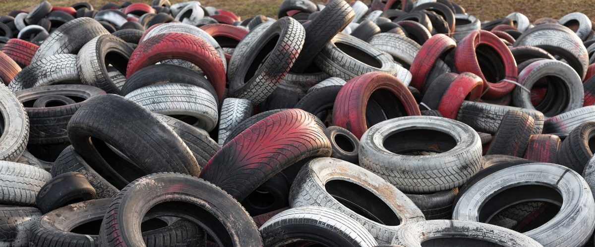 Variety of red white and black waste car tires piled in a big pile